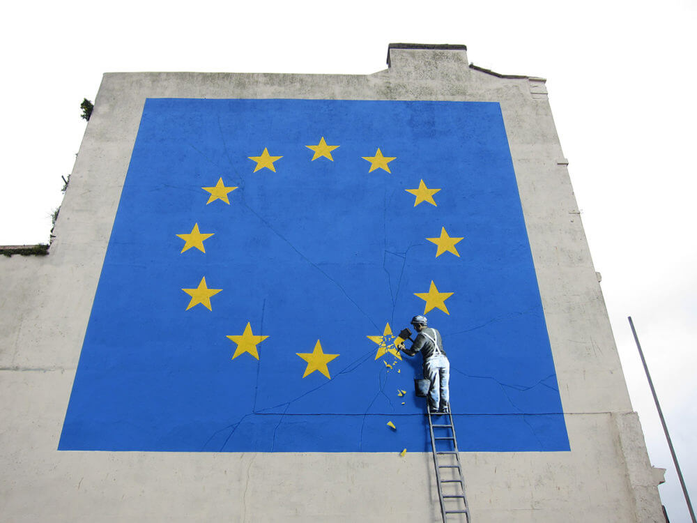 un homme peignant le drapeau de l'union européenne sur un bâtiment