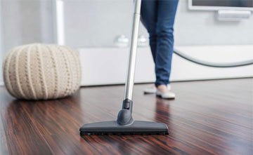 a woman is vacuuming the floor with a mop