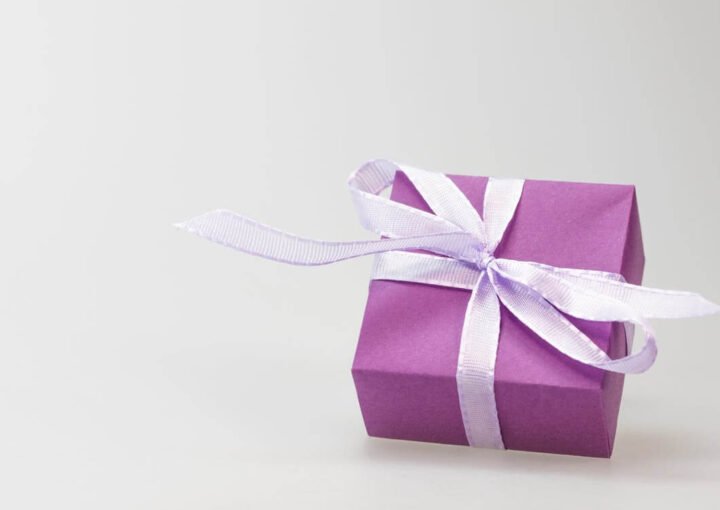 a purple gift box with a white ribbon
