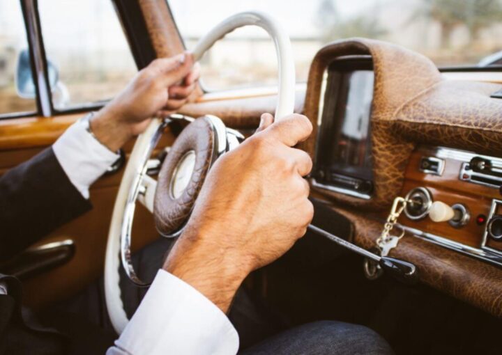 Las 5 razones principales por las que debería contratar un chofer 9 un hombre conduciendo un auto con las manos en el volante