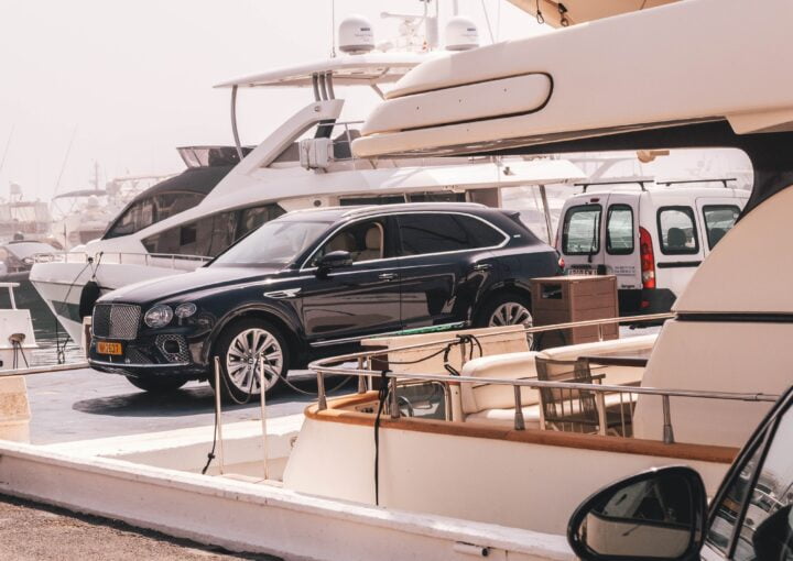Personal Privado 5* en Marbella | Lujo Exclusivo y Confort Supremo 8 un auto negro estacionado frente a un barco